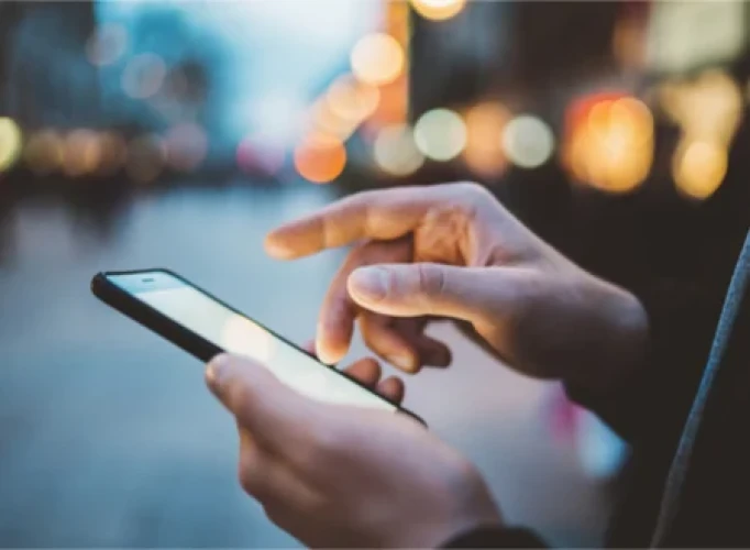 Handen die een smartphone bedienen om hun nieuwsbrief te lezen